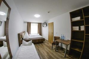 a room with a bed and a desk with a table at LOOK Hotel & Rooms in Crailsheim