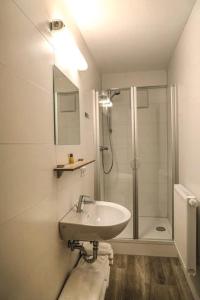 a white bathroom with a sink and a shower at LOOK Hotel & Rooms in Crailsheim