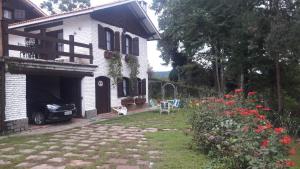 a white house with a car parked in the yard at Chalé pinheiro velho in Monte Verde