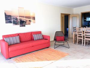 a living room with a red couch and a table at Varandas - Arrifana, com piscina, junto à praia in Praia da Arrifana