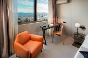 スプリトにあるRoyal Suites-Skyの窓のある客室で、オレンジ色の椅子とデスクが備わります。