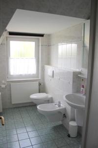 a white bathroom with a toilet and a sink at Skipper in Dorum-Neufeld