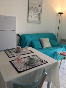 a living room with a table and a blue couch at residence parc de pontaillac in Vaux-sur-Mer