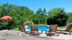 a group of chairs and an umbrella next to a pool at Rancho Escondido - Sólo Adultos - in Mina Clavero