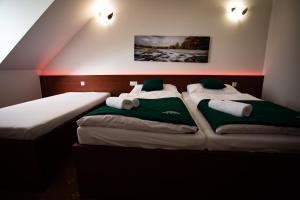 two beds in a room with green and white pillows at Penzión Poľovník in Moldava nad Bodvou