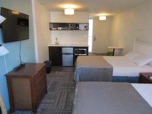 a hotel room with two beds and a kitchen at Waikiki Central Hotel - No Resort Fees in Honolulu
