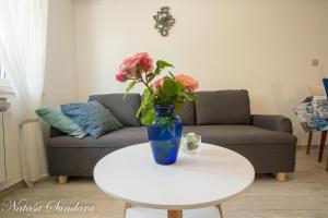 - un vase avec des fleurs sur une table dans le salon dans l'établissement Apartman Maria, à Pula
