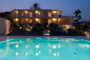 a large swimming pool in front of a house at night at La Scibina in Marina di Ragusa