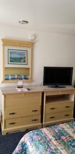 1 dormitorio con 1 cama y vestidor con TV de pantalla plana en Budget Lodge, en Newport News