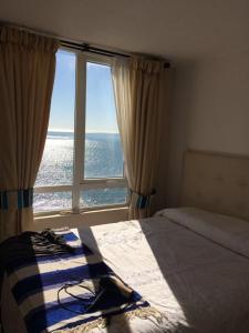 a bedroom with a bed and a large window at Depto. frente al mar in Tomé