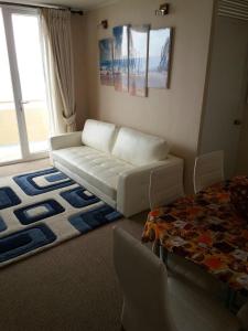 a living room with a white couch and a bed at Depto. frente al mar in Tomé