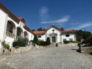 Une grande maison blanche avec une allée en pierre se trouve à l'avant. dans l'établissement Solar de Almeidinha, à Mangualde