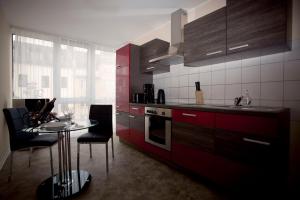 デュッセルドルフにあるアパートメンツ ホテル ピーターズバーグのキッチン(赤いキャビネット、テーブル、椅子付)