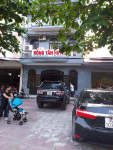 een vrouw met een baby in een kinderwagen voor een gebouw bij Khách Sạn Hồng Tấn in Thương Xà (2)
