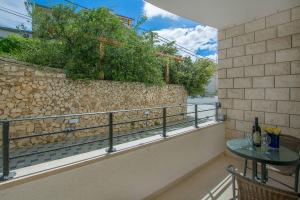 balcón con mesa y pared de piedra en Apartments Villa Aquamarine, en Duće