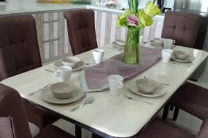 een tafel met borden en een vaas met bloemen erop bij Manee Home Kota Damansara in Kuala Selangor
