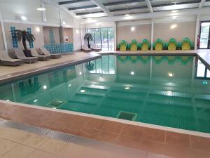 a large swimming pool in a building at Hot tub hols in lodge with roof terrace in Tattershall