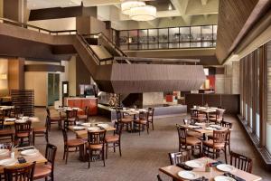 a restaurant with tables and chairs and a staircase at Ramada Plaza by Wyndham Regina Downtown in Regina
