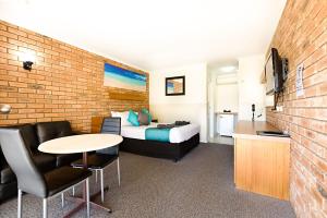 Habitación de hotel con cama, mesa y sillas en Statesman Motor Inn en Corowa