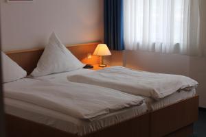 a bed with white sheets and a lamp next to a window at Filmhotel Lili Marleen in Potsdam