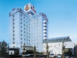 a hotel building with cars parked in a parking lot at Nagoya Kasadera Hotel in Nagoya