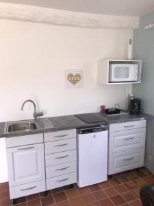 a white kitchen with a sink and a microwave at Le Poule House in Guérard
