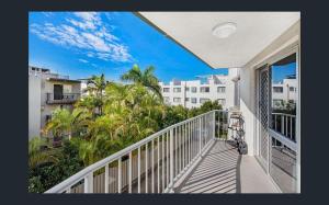 a balcony with a view of palm trees and buildings at Kings Beach Retreat in Caloundra