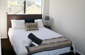 a bedroom with a white bed with pillows and a window at Kings Beach Retreat in Caloundra