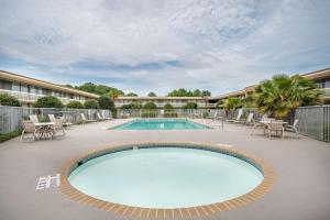 a swimming pool on a patio with chairs and a building at Quality Inn Baton Rouge East I-12 in Baton Rouge