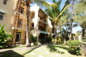 an exterior view of a building with palm trees at Villas Pingouin in Blue Bay