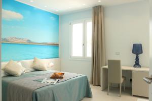 a bedroom with a bed with a desk and a window at 103 Boutique Hotel Stintino in Stintino