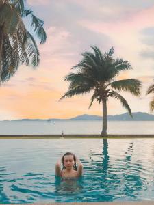 una donna in una piscina con una palma di D-Lux 4 bed beachfront apartment with sea view a Panwa Beach