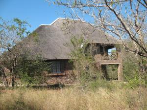 an old stone house with a thatched roof at Crowe's Nest in Marloth Park