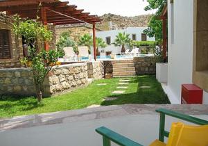 un patio trasero con sillas y una pared de piedra en Patmos Garden en Skala