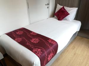 uma cama com um cobertor vermelho e branco em Signature International Hotel China Town em Kuala Lumpur