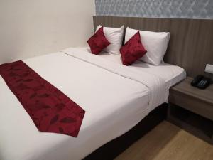 uma cama branca com almofadas vermelhas com em Signature International Hotel China Town em Kuala Lumpur