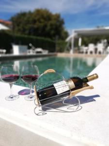 a bottle of wine and two glasses next to a pool at Apartmani Anđelo, Tommy, Leon in Bibinje
