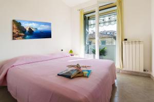 um quarto com uma cama cor-de-rosa com um livro em Appartamenti Palmaria em Diano Marina