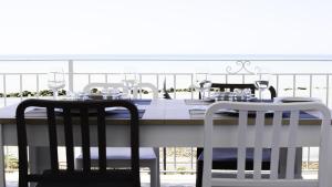 une table blanche avec deux chaises et une table avec des verres dans l'établissement Terrazza sul Mediterraneo, à Seccagrande