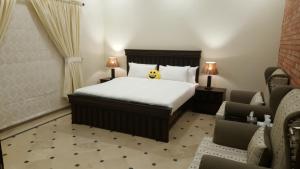 ein Hotelzimmer mit einem Bett und zwei Stühlen in der Unterkunft Mulberry Residence Family Rooms in Islamabad