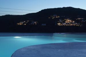 a night view of a swimming pool with a city at Mykonos Pantheon in Kalo Livadi