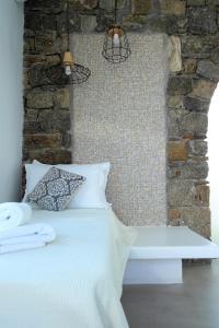 a bedroom with a white bed and a brick wall at Mykonos Pantheon in Kalo Livadi