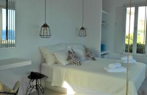 a white bedroom with a bed with white sheets and pillows at Mykonos Pantheon in Kalo Livadi