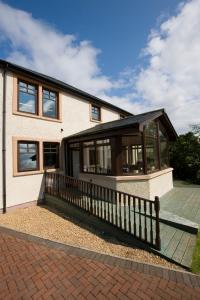 uma casa com um alpendre com uma cerca de madeira em Arisaig Guest House em Inverness