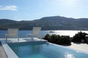 two chairs sitting on the edge of a swimming pool at Mykonos Pantheon in Kalo Livadi