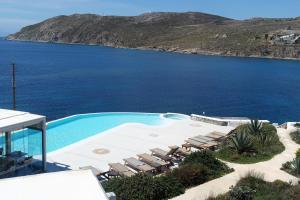 a swimming pool with lounge chairs and the ocean at Mykonos Pantheon in Kalo Livadi
