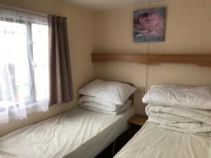 two twin beds in a room with a window at 6 berth Golden sands (Torino) in Ingoldmells