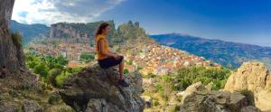 a woman sitting on a rock overlooking a city at Su Marmuri in Ulassai