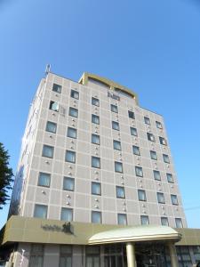 un alto edificio bianco con un cielo blu sullo sfondo di Hotel Benex Yonezawa a Yonezawa