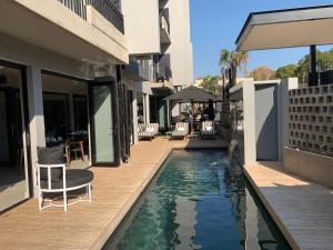 a swimming pool next to a building with chairs at Trendy Melrose Apartment in Johannesburg